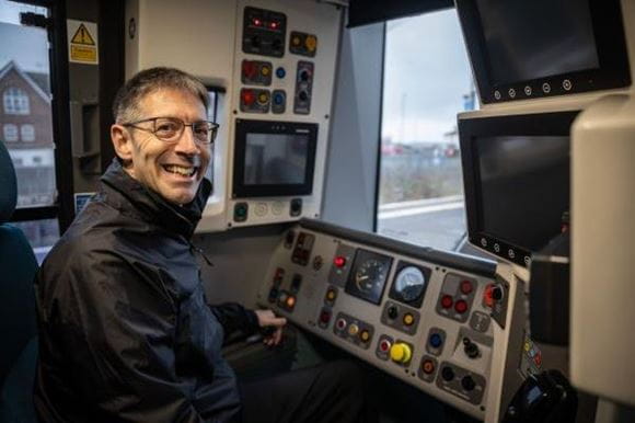 Train driver Paul Freegard smiling at the camera while sitting in the train driver's cab