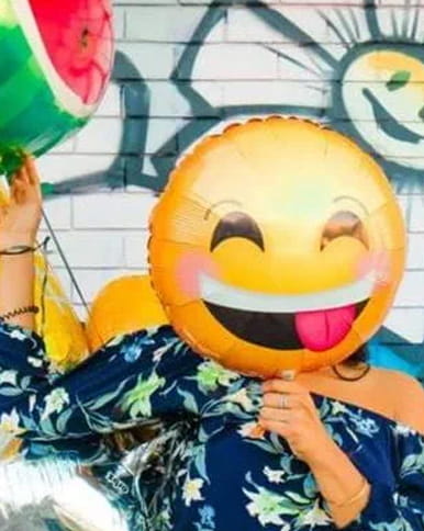 A person holding up a balloon with a smiley face on it
