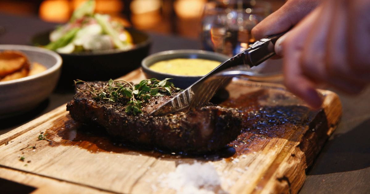 Stock image of a person cutting into a steak