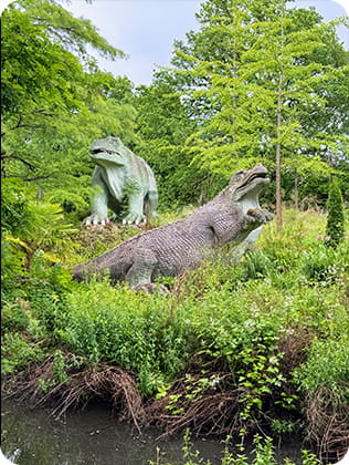 Dinosaur statues in a green area of trees and shrubs