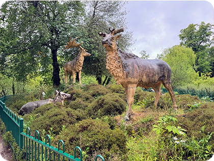 Statues of Irish Elk in a green area of trees and shrubs