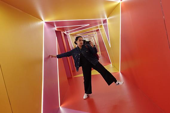 A girl standing in an orange and yellow twisted hallway