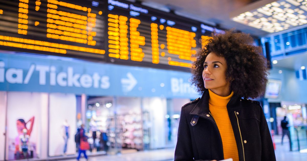 Woman in a train station in front of a departure board