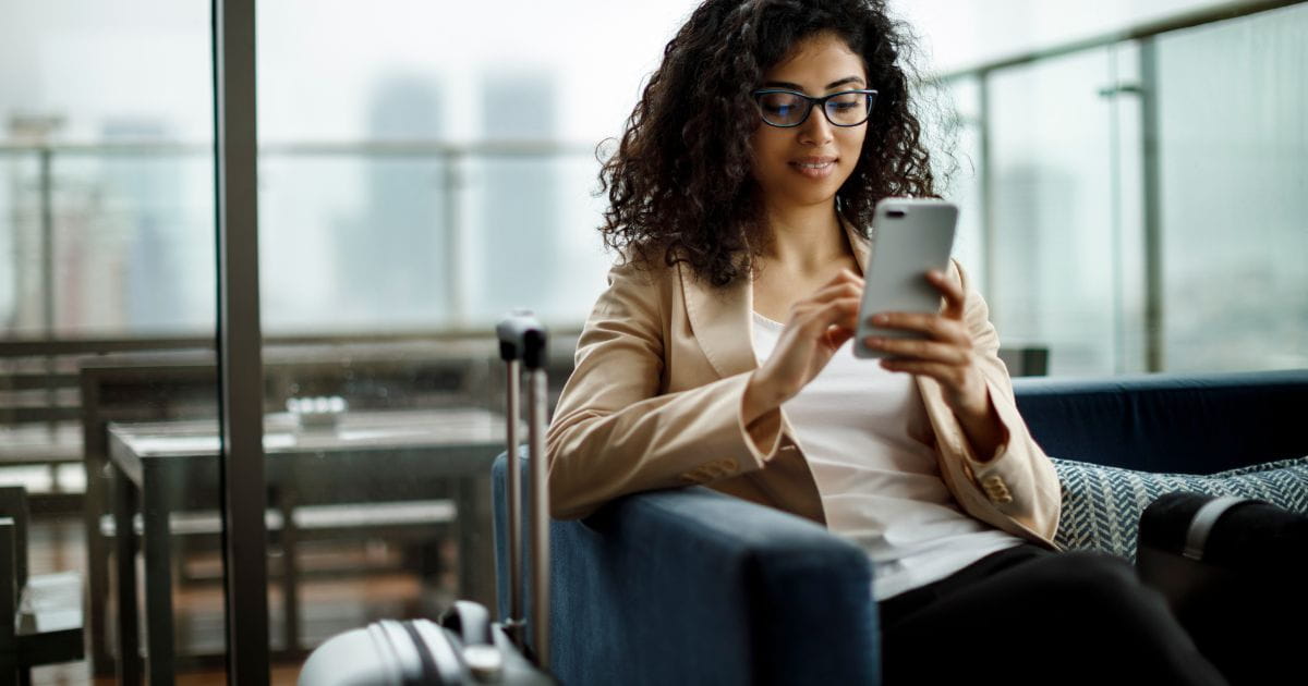 Woman with a suitcase using a smartphone