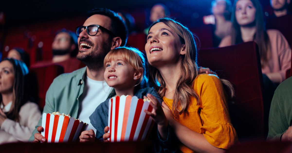 family eating popcorn watching a film at the cinema