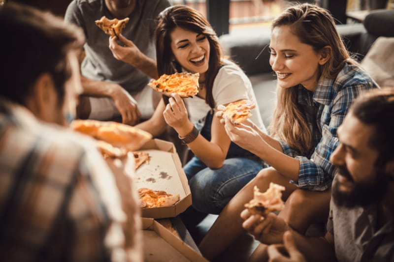 a group of people sitting at a table eating pizza