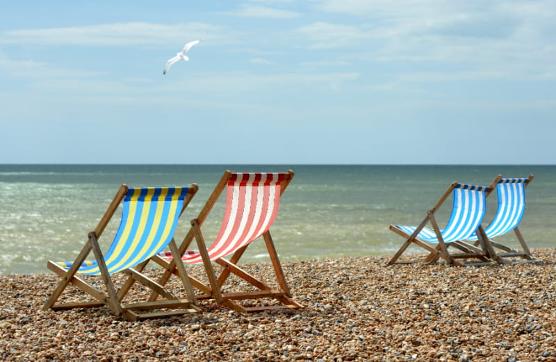 a group of lawn chairs sitting on top of a sandy beach
