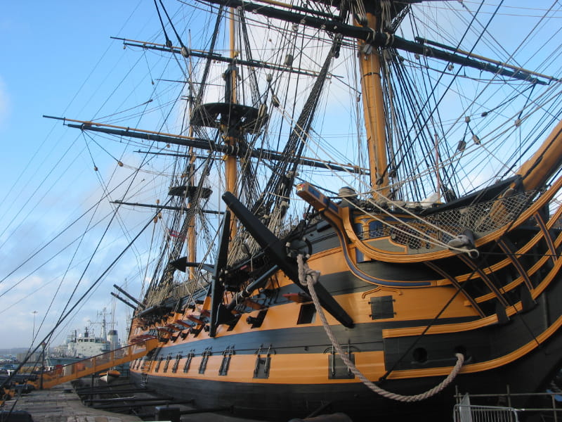 a large ship in the background with HMS Victory in the background