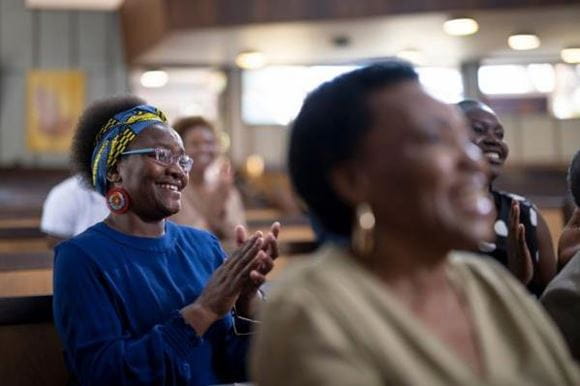 A group of women seated smiling one is clappnig