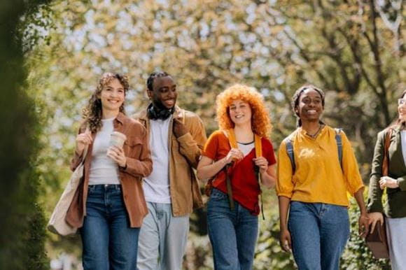 A group of students walk through campus smiling