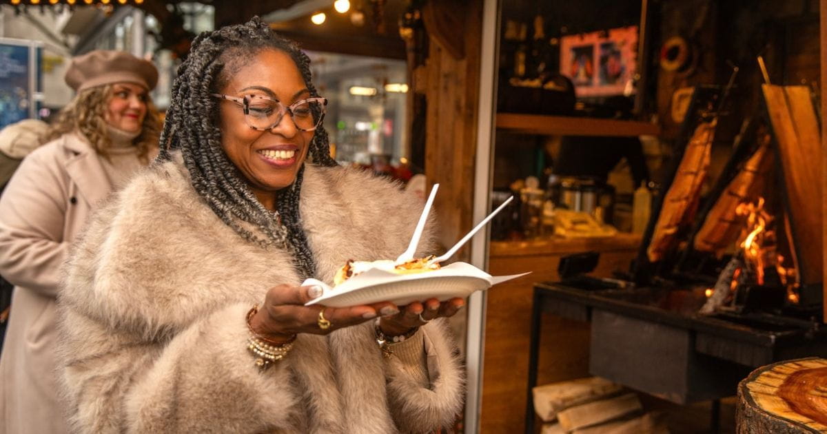 Smiling woman with festive food at a Christmas market