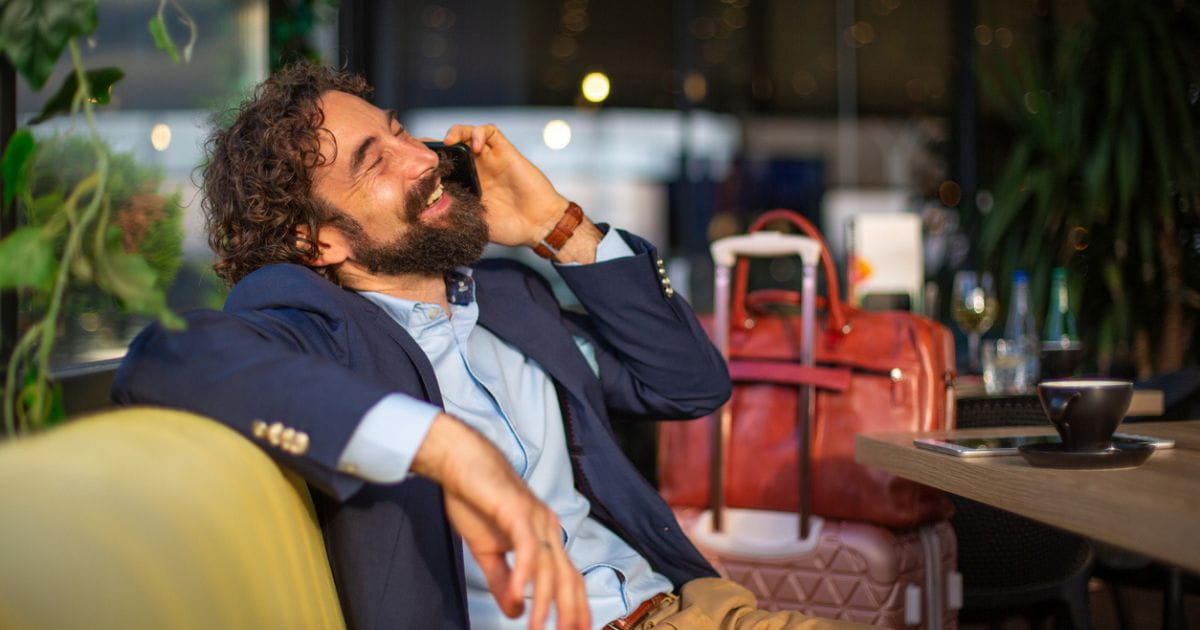 Businessman on the phone with luggage in an airport lounge