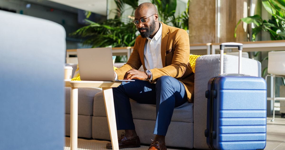Man in an airport lounge with luggage and laptop