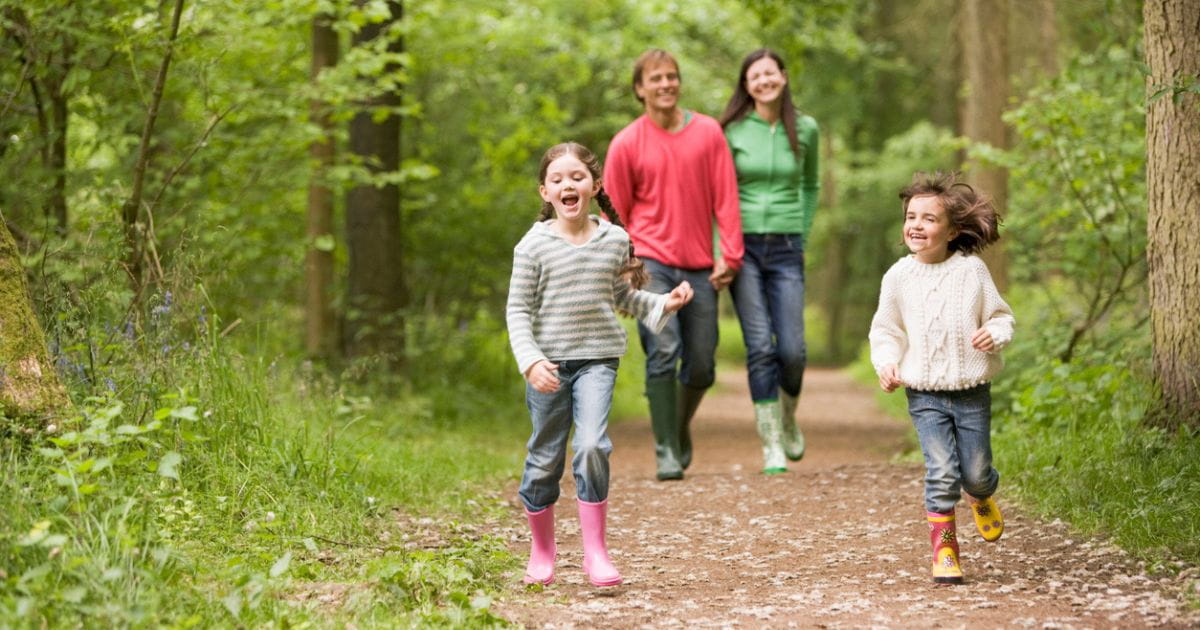 A family wearing wellington boots walking through woodland