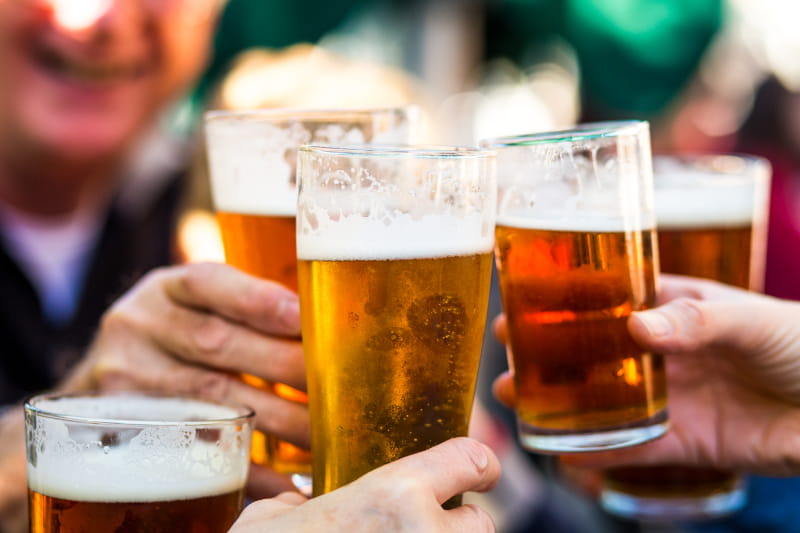 a hand holding a glass of beer on a table